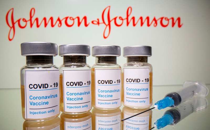 Frascos rotulados como de vacina contra Covid-19 em frente a logo da Johnson & Johnson em foto de ilustração